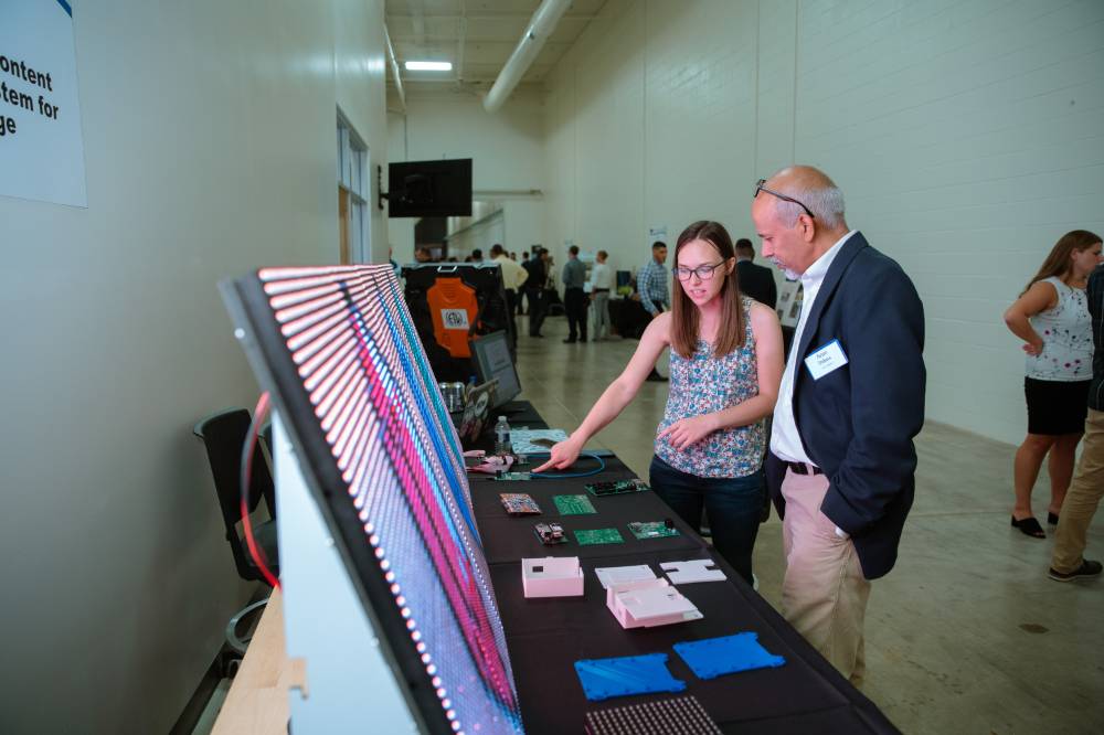 An engineering student explains her LED signage project to a guest at the Engineering Design Project Preview